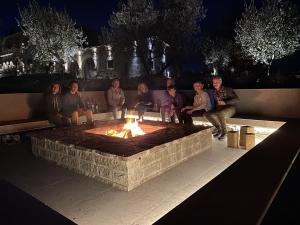 un groupe de personnes assises autour d'un foyer extérieur la nuit dans l'établissement Villa Paladini, à Montefiascone
