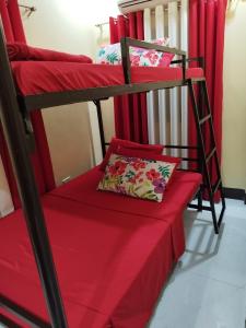a room with two bunk beds with red sheets at Jumong's Transient in Bantay