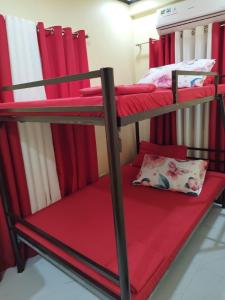 a couple of bunk beds in a room with red curtains at Jumong's Transient in Bantay