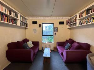 two purple couches in a room with bookshelves at Around The World Backpackers in Christchurch