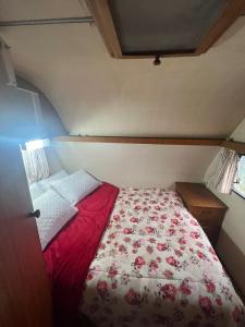 um quarto com uma cama com um edredão vermelho e branco em Trailer Oasis em Lavras Novas