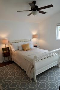 a bedroom with a white bed with a ceiling fan at Cozy Family Hideaway, sleeps 8, 4 tv's yard, shops in Simi Valley