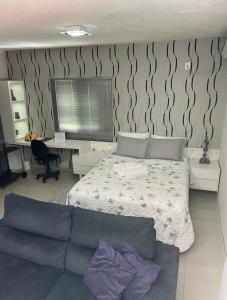 1 dormitorio con cama, sofá y escritorio en Loft com linda vista na Rota do Enxaimel, en Pomerode