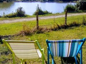 dwa krzesła siedzące w trawie blisko wody w obiekcie Romantic holiday home in Précy with garden w mieście Précy