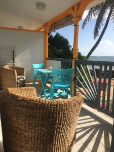 un porche con sillas y una mesa en una terraza con vistas al océano en Résidence Nature Ocean - M&P Concept, en Cadet