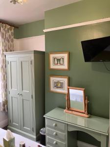 Un dormitorio con paredes verdes y un escritorio con espejo. en Broadlands Guest House, en Stratford-upon-Avon