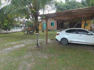 un coche blanco estacionado junto a una palmera en Casa Guaiú, en Santa Cruz Cabrália