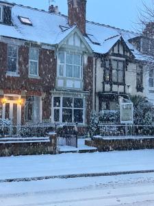 uma casa na neve com neve em Broadlands Guest House em Stratford-upon-Avon