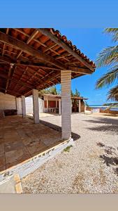 a patio with a wooden roof and a palm tree at Casa de Praia, na Praia do Presídio in Aquiraz