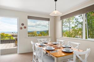 a dining room with a table and chairs and windows at Great Lake Getaway - Taupo in Taupo