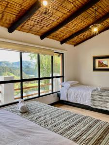 two beds in a room with a large window at Hostería El Troje Experience in Riobamba