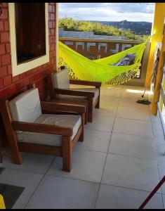 Un balcón con 2 sillas y una hamaca. en Casa clima de montanha, en Gravatá