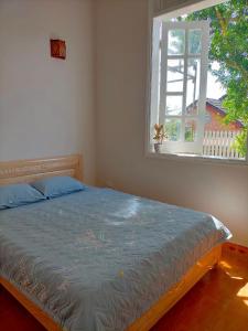 um quarto com uma cama com uma colcha azul e uma janela em Ly's homestay em Gia Nghĩa