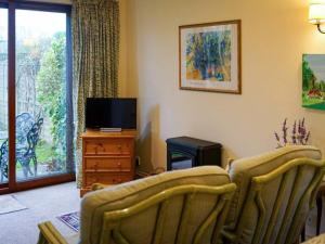 a living room with two chairs and a television at Honeysuckle Cottage in North Mundham