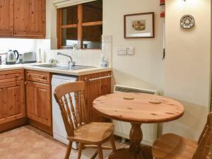 a kitchen with a wooden table and a sink at Honeysuckle Cottage in North Mundham