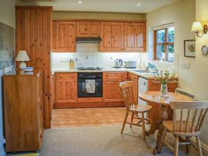 a kitchen with wooden cabinets and a table and chairs at Honeysuckle Cottage in North Mundham