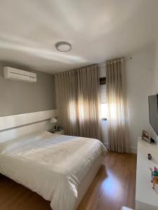 1 dormitorio con cama blanca y ventana en Aptoaconchegantepoa, en Porto Alegre
