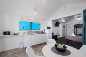 a kitchen and living room with a table and chairs at Kaiteriteri Reserve Cabins in Kaiteriteri