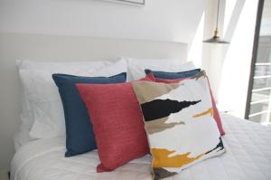 a white bed with colorful pillows on it at Cozy Stays Cayala Apartments 602 in Guatemala