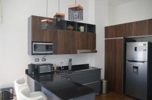 a kitchen with a black counter top and a refrigerator at Cozy Stays Cayala Apartments 602 in Guatemala