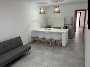 una cocina con sofá y una isla de cocina con taburetes en Casas/deptos a estrenar en Necochea