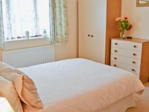 een slaapkamer met een bed, een dressoir en een raam bij Combe Cairn in Millom