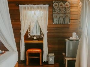 a bedroom with a bed and a mirror and a stool at Garden Cottage Lembongan & Hostel in Nusa Lembongan