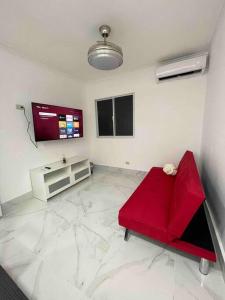un soggiorno con divano rosso e TV di Apartment Av. Republica de Colombia US embassy a Santo Domingo