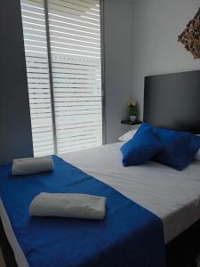 Una cama grande con almohadas azules encima. en Colibrí Cafeterito, en Montenegro