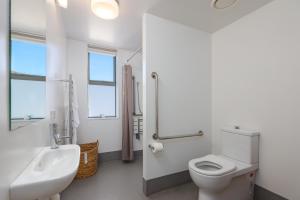 a white bathroom with a toilet and a sink at Kaiteriteri Reserve Apartments in Kaiteriteri