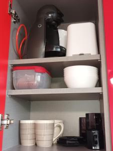 a shelf with dishes and cups in a cabinet at STUDIO ROUGE GORGE TARTANE in La Trinité