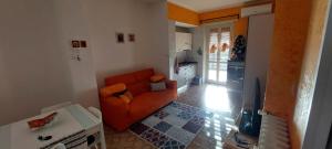 sala de estar con sofá naranja y cocina en Casa dei Nonni - comodo Metro e Stadio Juve, en Turín