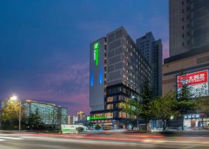 un edificio alto con una señal verde por la noche en Holiday Inn Express Linyi North New District by IHG, en Linyi