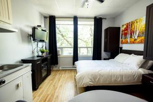 a small room with a bed and a television at Le Citadin in Rouyn