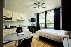 a bedroom with a bed and a table and a kitchen at Le Citadin in Rouyn-Noranda