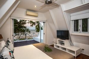 a bedroom with a bed and a television and a balcony at Cottonwood Beachfront in Oak Beach