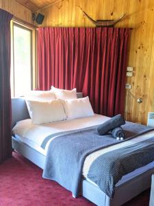 a bedroom with a large bed with red curtains at The Beach Cabin in Fingal