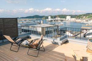 une personne assise sur une chaise sur une terrasse avec vue dans l'établissement LAMP Iki, à Iki