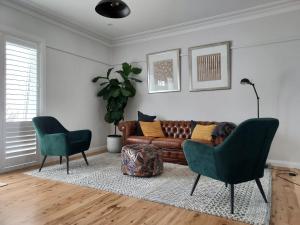 sala de estar con sofá y 2 sillas en Garden of Eden Boutique Cottage and Spa en Doonside