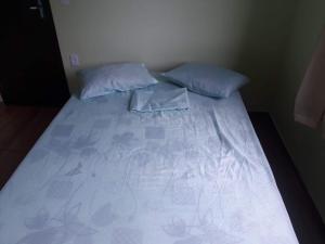 Cama en habitación con 2 almohadas en HOSPEDAGEM DA ROSE 3, en Marataízes