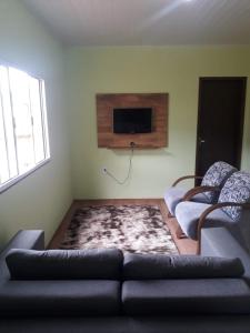 a living room with a couch and a flat screen tv at HOSPEDAGEM DA ROSE 3 in Marataizes