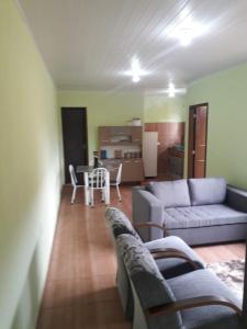 a living room with a couch and a table with chairs at HOSPEDAGEM DA ROSE 3 in Marataizes