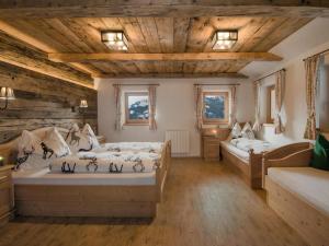 a bedroom with two beds and wooden ceilings at Large hut in the Pinzgau with a great view and its own sauna hut in Dorf