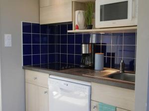 eine Küche mit blauen Wandfliesen und einem Geschirrspüler in der Unterkunft Residence La Côte d'Émeraude, Saint-Cast-le-Guildo, terraced house for 4 people in LʼIsle-Saint-Cast