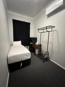 1 dormitorio con 1 cama y escritorio con escritorio en Adelaide Pulteney Motel, en Adelaida