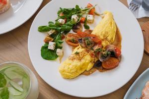 a white plate of food with an omelet and vegetables at Asri Cinta Villa Ubud in Ubud +42 photos
