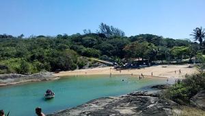 un barco en un río con gente en una playa en Setiba Beach House, en Guarapari