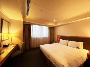 a hotel room with a large bed and a desk at Fuward Hotel Tainan in Tainan