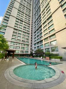 un bambino in una piscina di fronte a edifici alti di ORTIGAS 2 Br Corner Unit With 2 Queen Across Shangrila a Manila