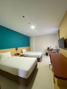 a hotel room with two beds and a desk at Erbe Style Jayapura Papua By Horison in Jayapura